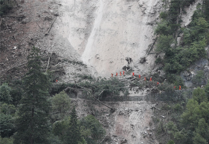 8月10日，一组搜救队伍通过九寨沟景区五花海到熊猫海的滑坡路段。
