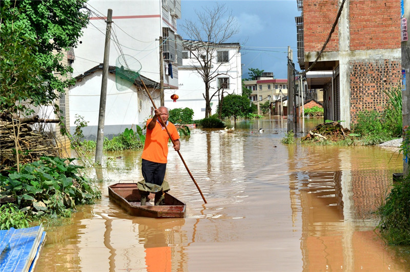 7月3日，桂林市雁山区雁山镇的一名村民撑船驶出被洪水淹没的村庄。