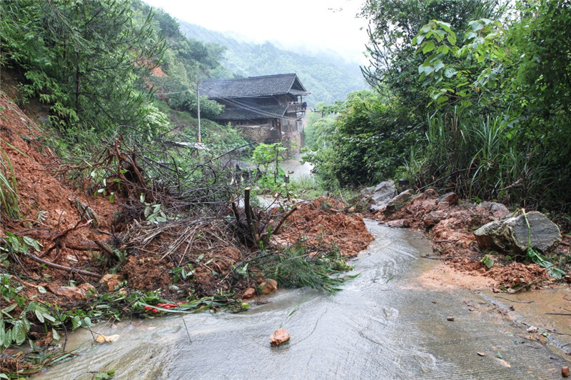 在湖南省邵阳市绥宁县长铺子苗族侗族乡芷坪村，被大雨冲下的山石和泥土阻塞道路（6月26日摄）。