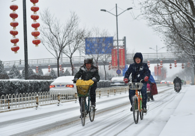 2月21日，在太原市滨河东路，两位市民冒雪骑行。