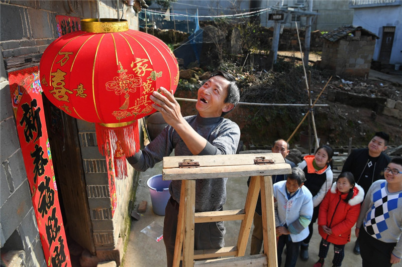 江西鄱阳县古县渡镇张家坽村村民张雪运（左一）在家门口挂灯笼，喜迎新春佳节（1月24日摄）。