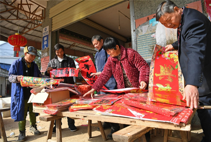 江西鄱阳县古县渡镇张家坽村村民在集市上选购春联（1月24日摄）。