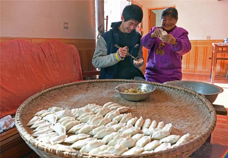 江西鄱阳县古县渡镇张家坽村村民胡桂花（右）和孙子在家里做米粑（1月24日摄）。